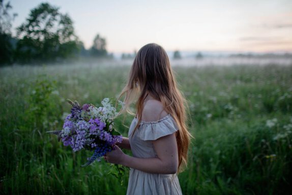 Nainen niityllä kädessään kukkia