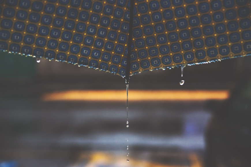 Kuvassa vesi tippuu sateenvarjon reunasta.